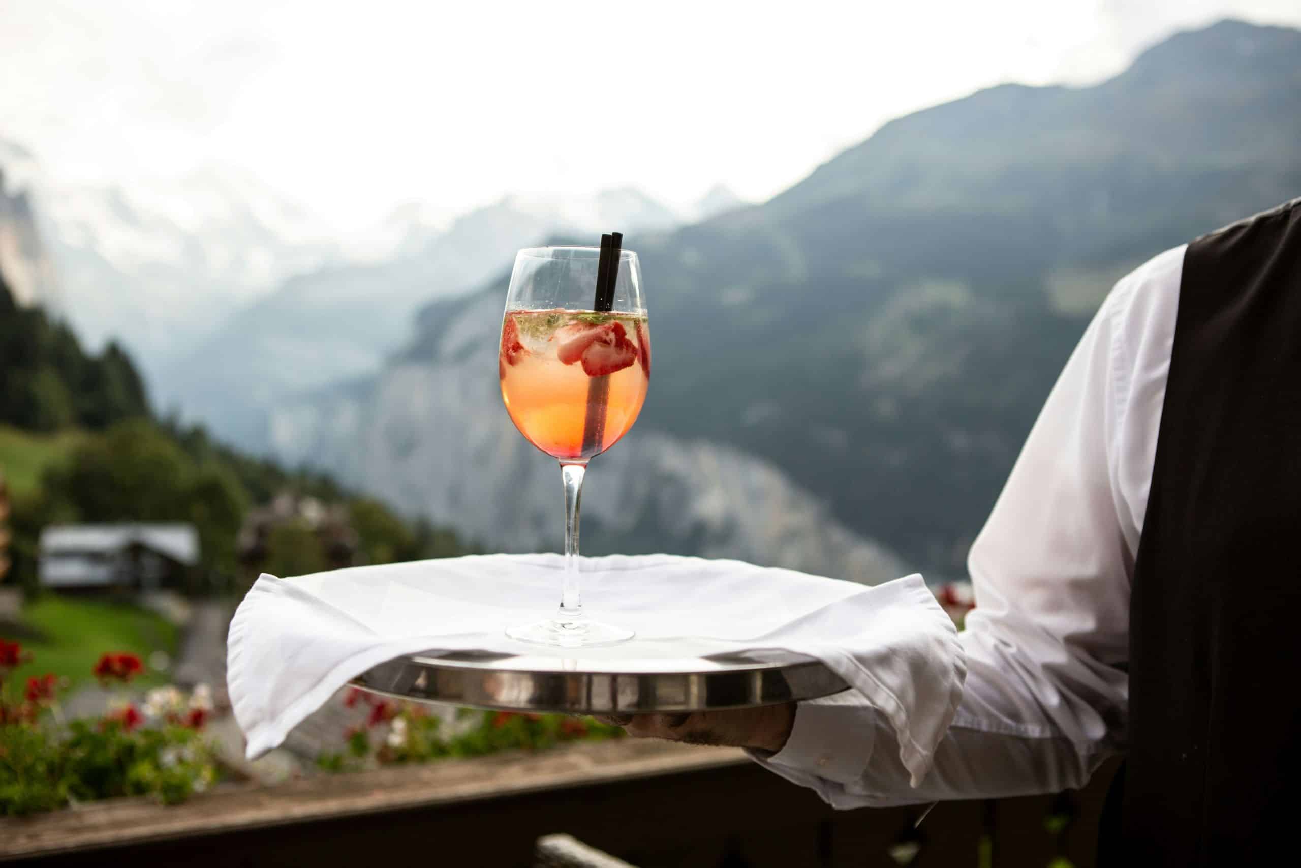 waiter holding glass of wine in the mountains